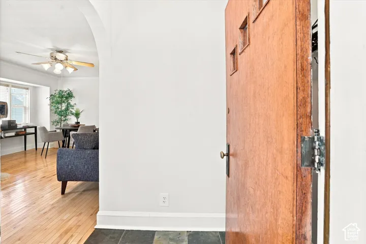 Welcoming entry featuring solid wood-finish flooring, crisp white walls, and an arched ceiling detail with ceiling fan