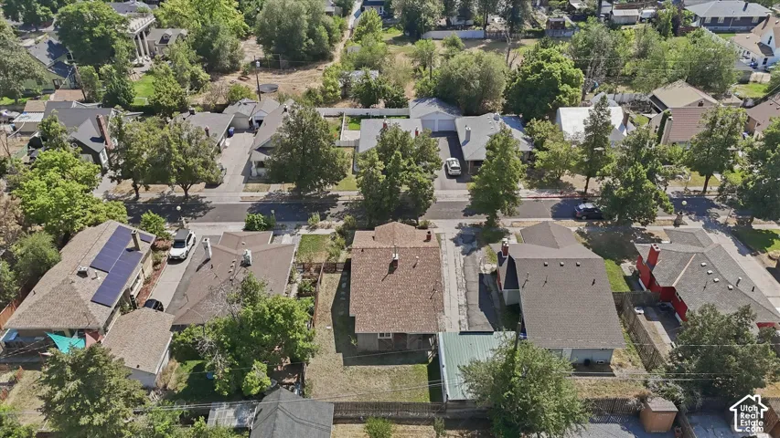 Aerial view showcasing this residential property featuring a composition roof, mature landscaping with established trees throughout the lot, and a well-defined footprint