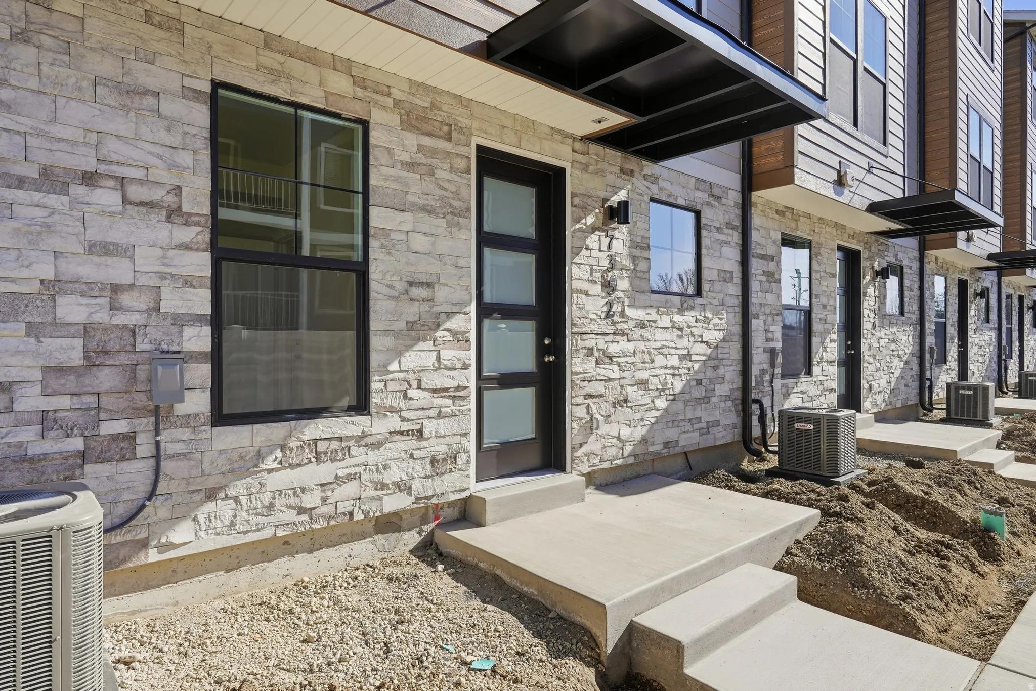 Stone veneer exterior with black window frames and a contemporary glass-paneled entry door