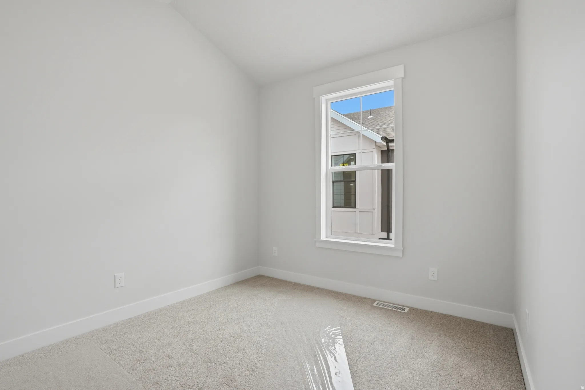 Interior room featuring a single window, light-toned carpeting, and white baseboards