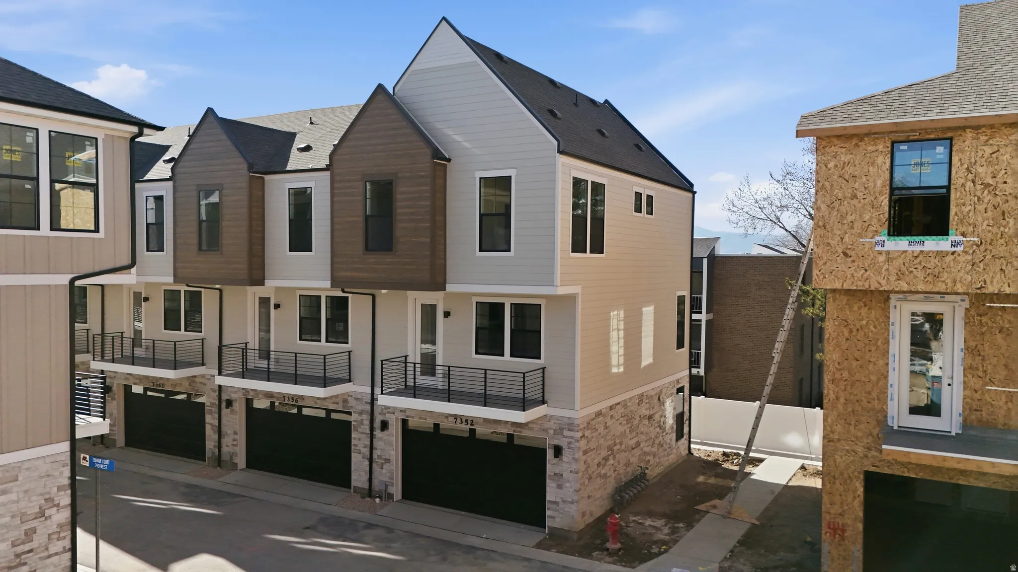 Contemporary townhome exterior featuring multi-level design with light-colored siding and dark gable accents