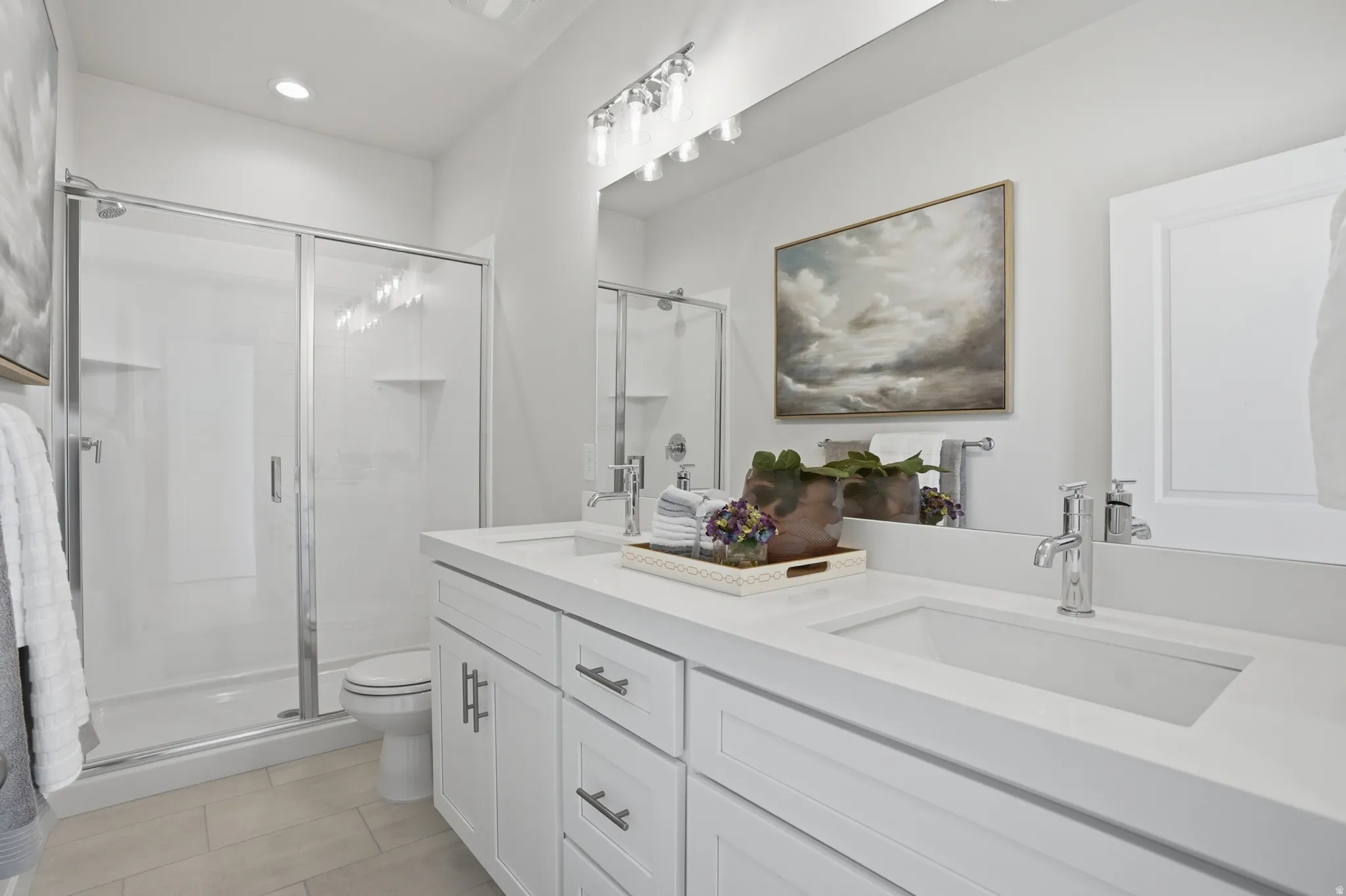 Bathroom featuring a dual-sink vanity with white cabinetry, a light-toned countertop, and chrome fixtures