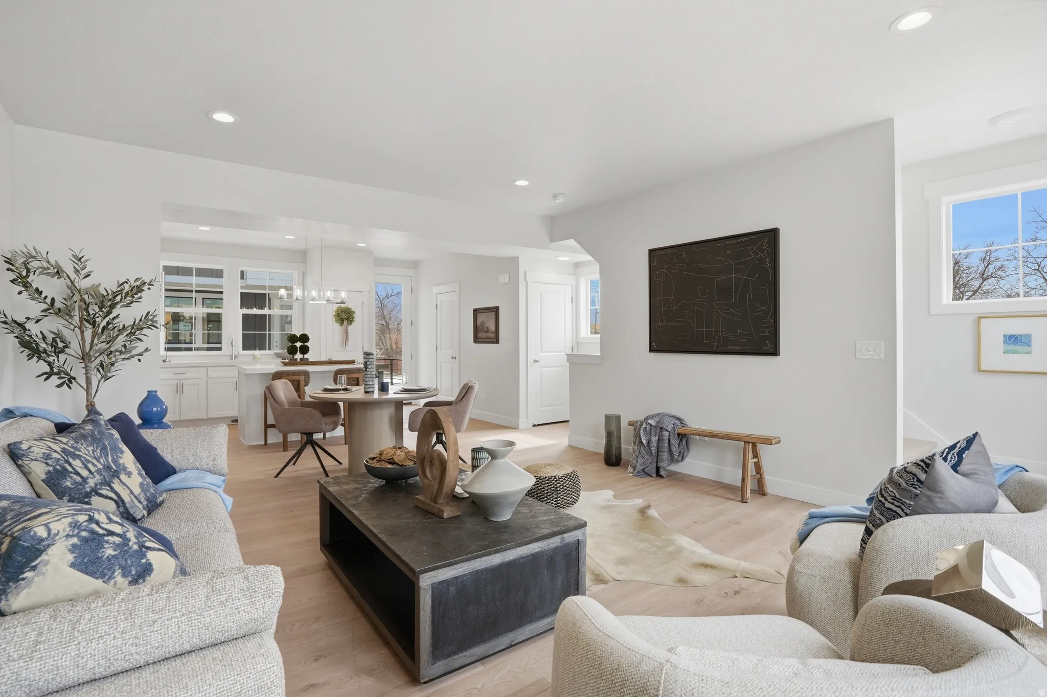 Open-concept living area featuring light wood-finish flooring, recessed lighting, and bright white walls