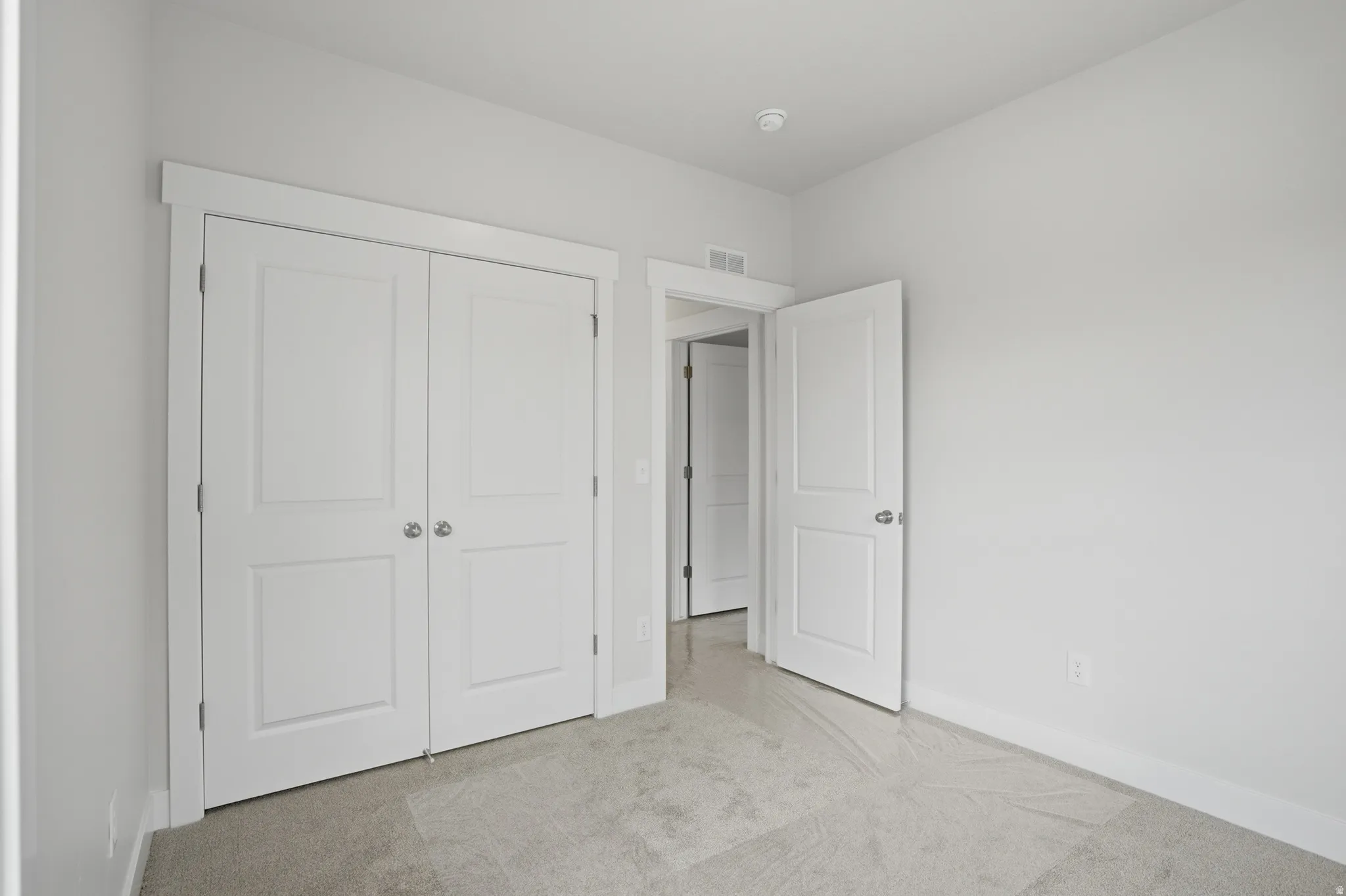 Carpeted room featuring a double-door closet with paneling, white trim, and a neutral wall color