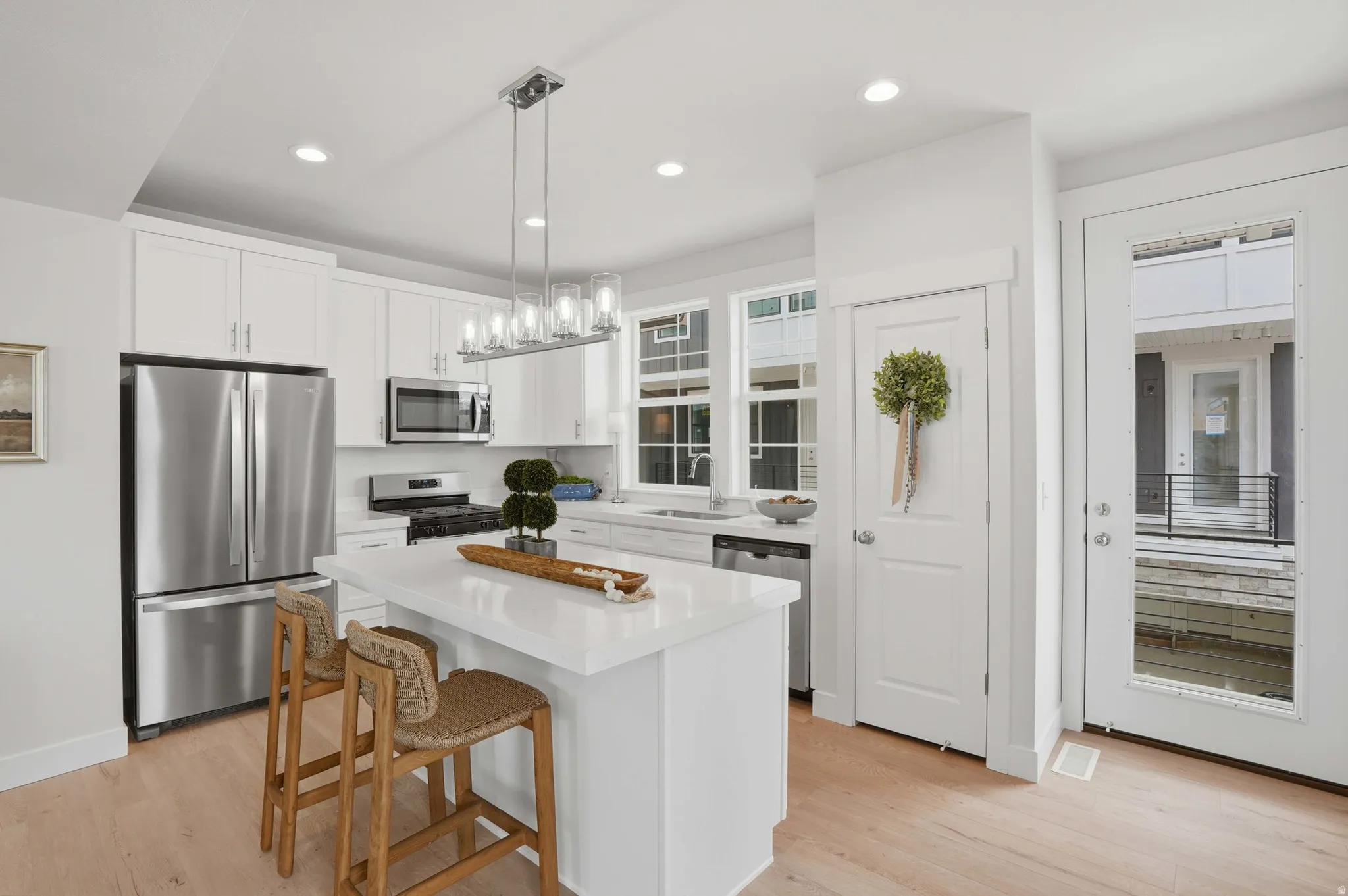 Modern kitchen featuring white cabinetry, stainless steel appliances, a center island with countertop seating, and light wood-finish flooring