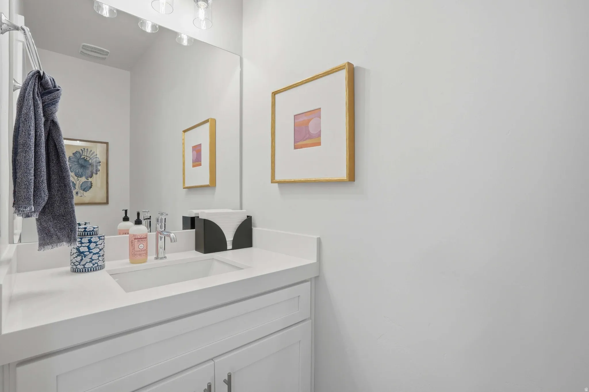 Contemporary vanity featuring an undermount sink, a polished chrome faucet, and a large wall-mounted mirror with overhead lighting