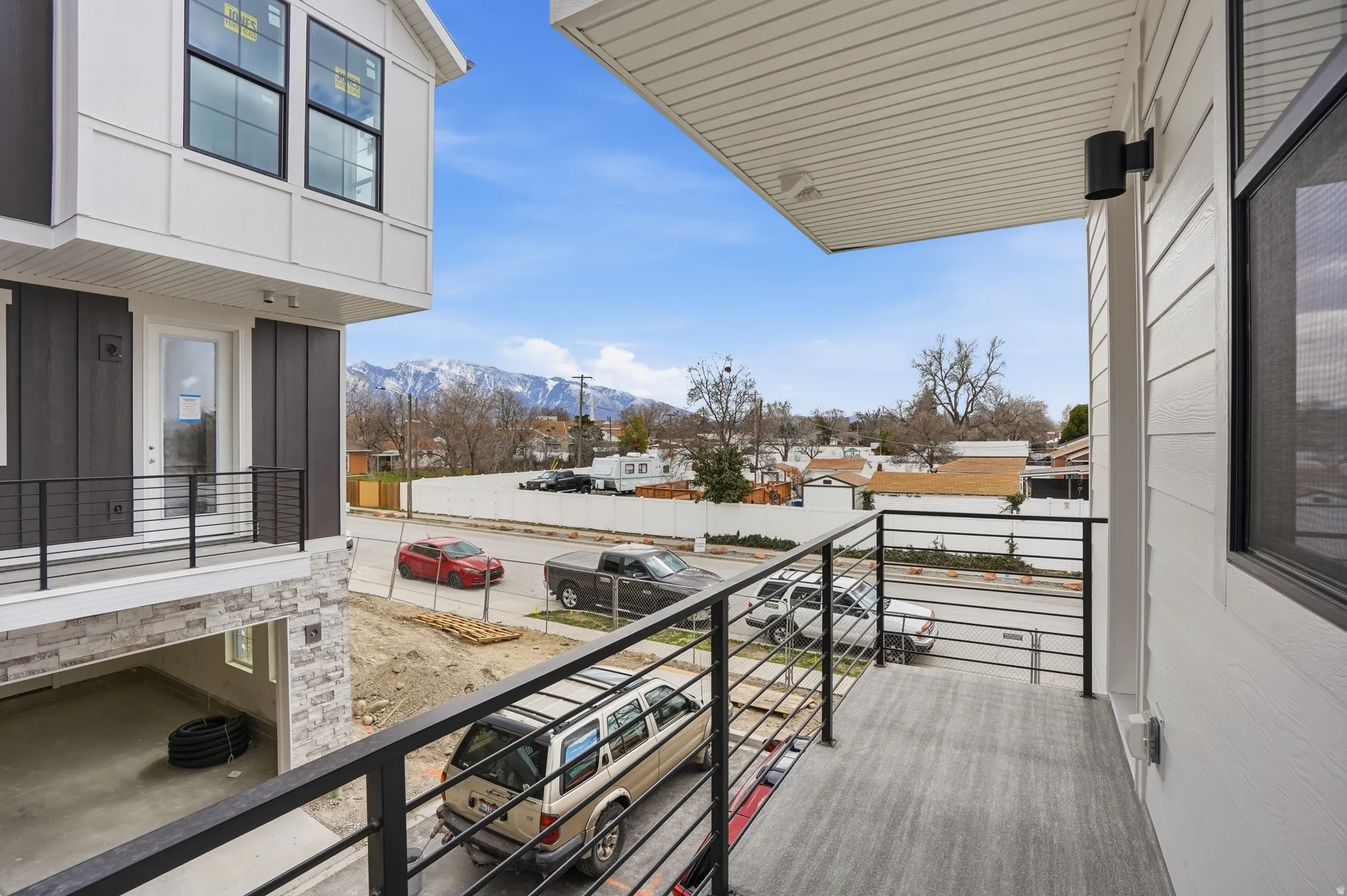 Balcony featuring modern metal railings, textured plank flooring, and an exterior wall sconce