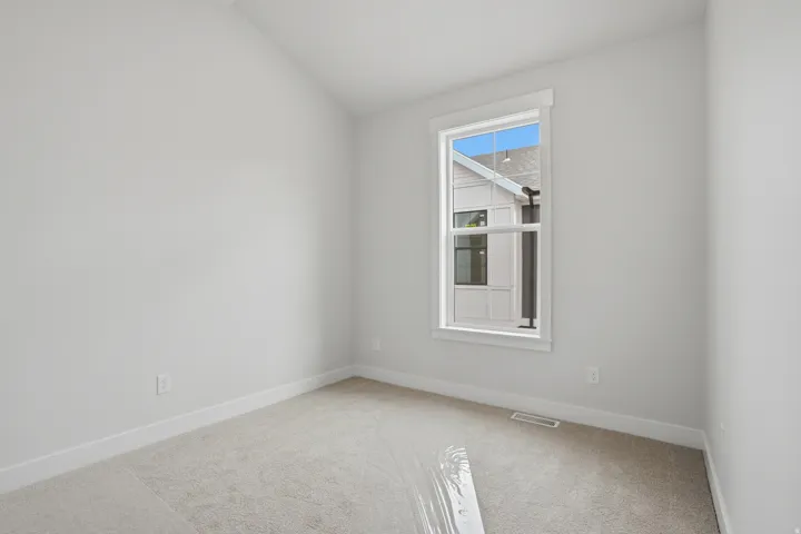 Interior room featuring a single window, light-toned carpeting, and white baseboards