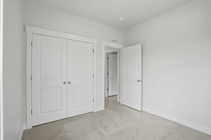 Carpeted room featuring a double-door closet with paneling, white trim, and a neutral wall color