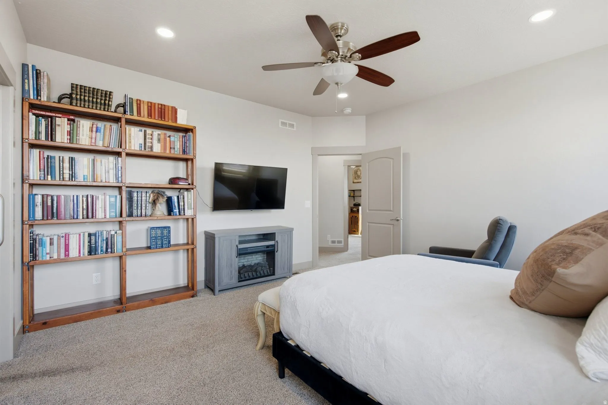 Carpeted room featuring a ceiling fan with integrated lighting, recessed lighting, and a built-in wooden bookshelf