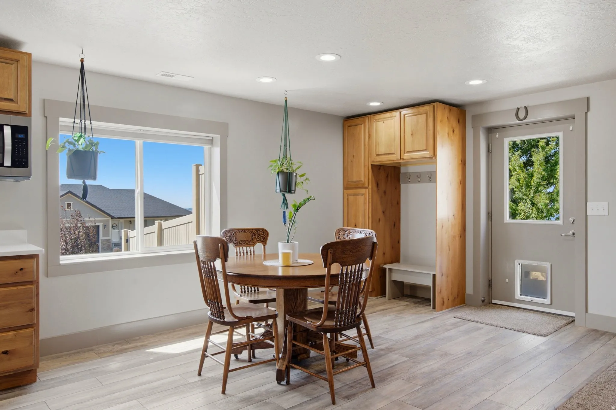 Bright, open dining area featuring a round pedestal table with wood-finish flooring throughout