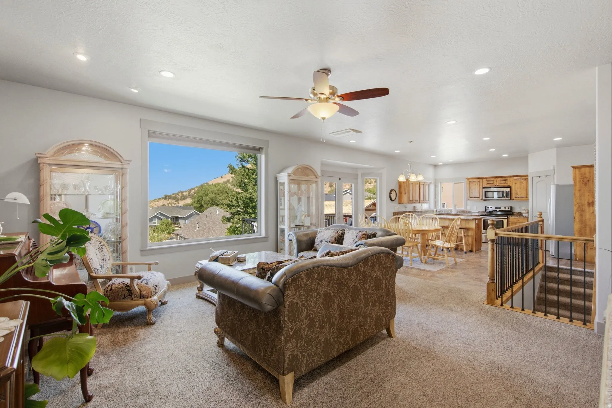 Open-concept great room showcasing soaring ceilings, recessed lighting, and a ceiling fan with wood-finish blades