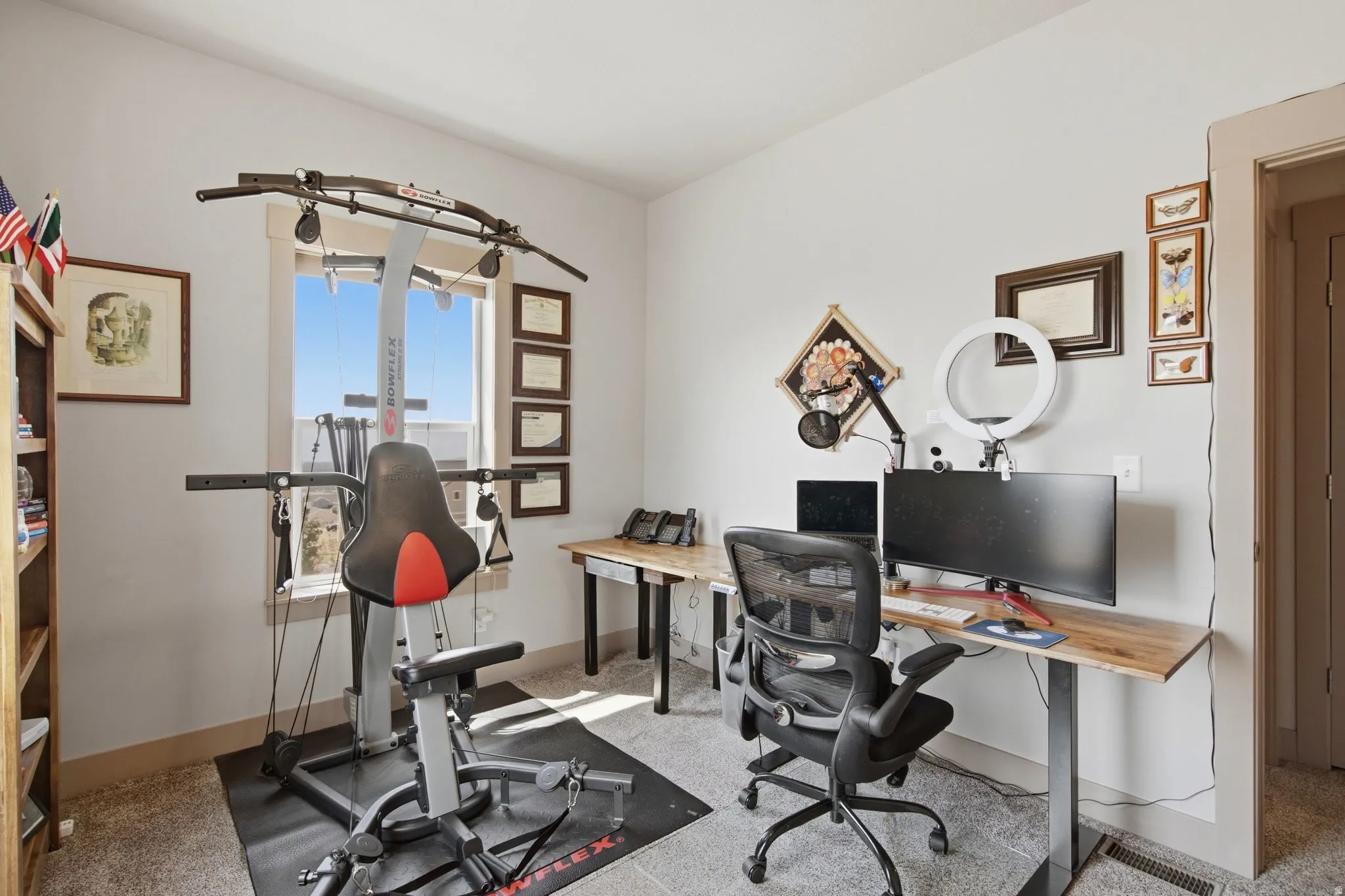 Home Office featuring dual workstations with ergonomic seating, ample natural light from expansive windows framing iconic city skyline views, built-in desk surfaces with integrated storage, and professional-grade task lighting