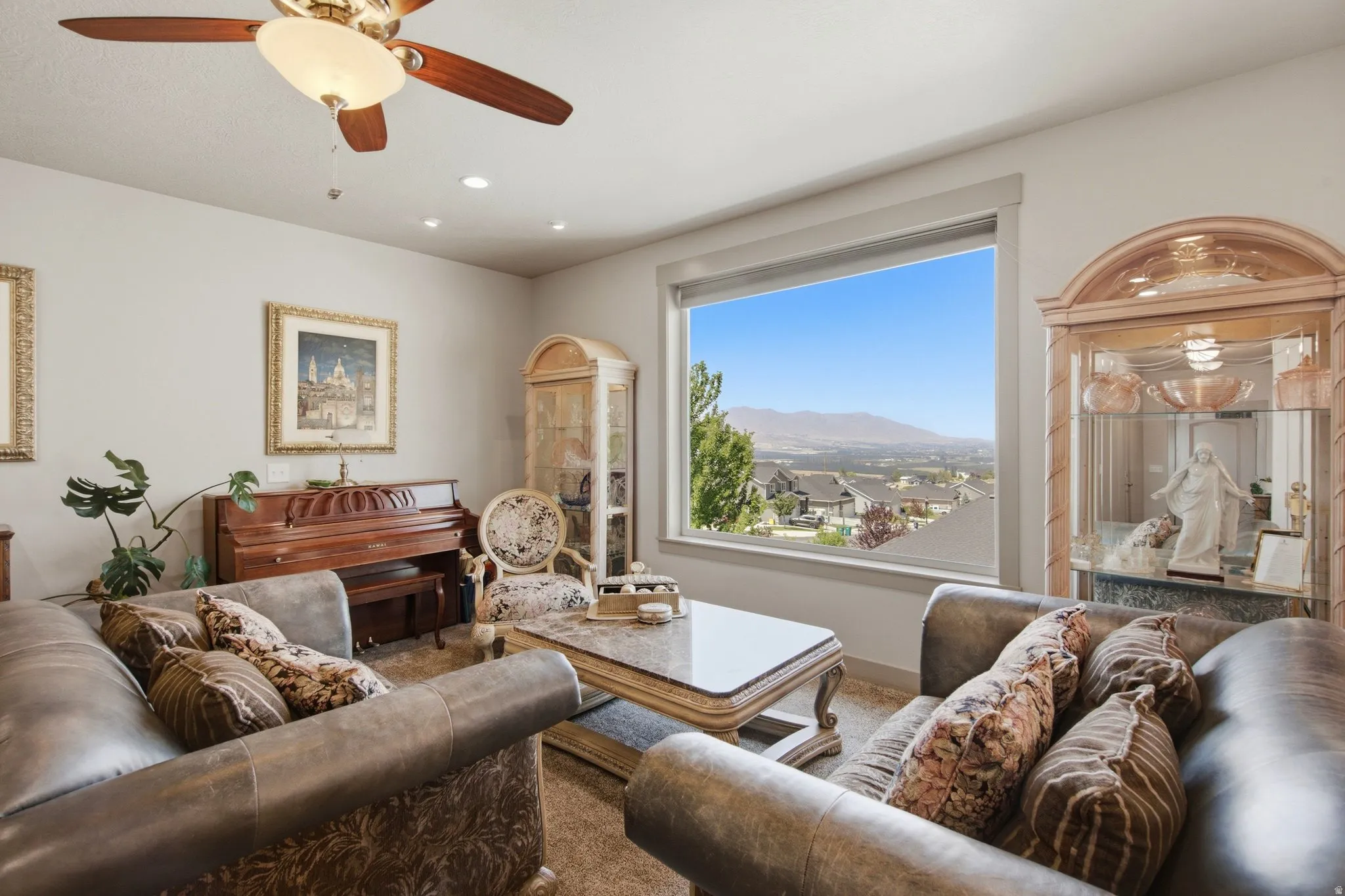 Elegant living room showcasing hardwood flooring, a ceiling fan with integrated lighting, and a grand piano