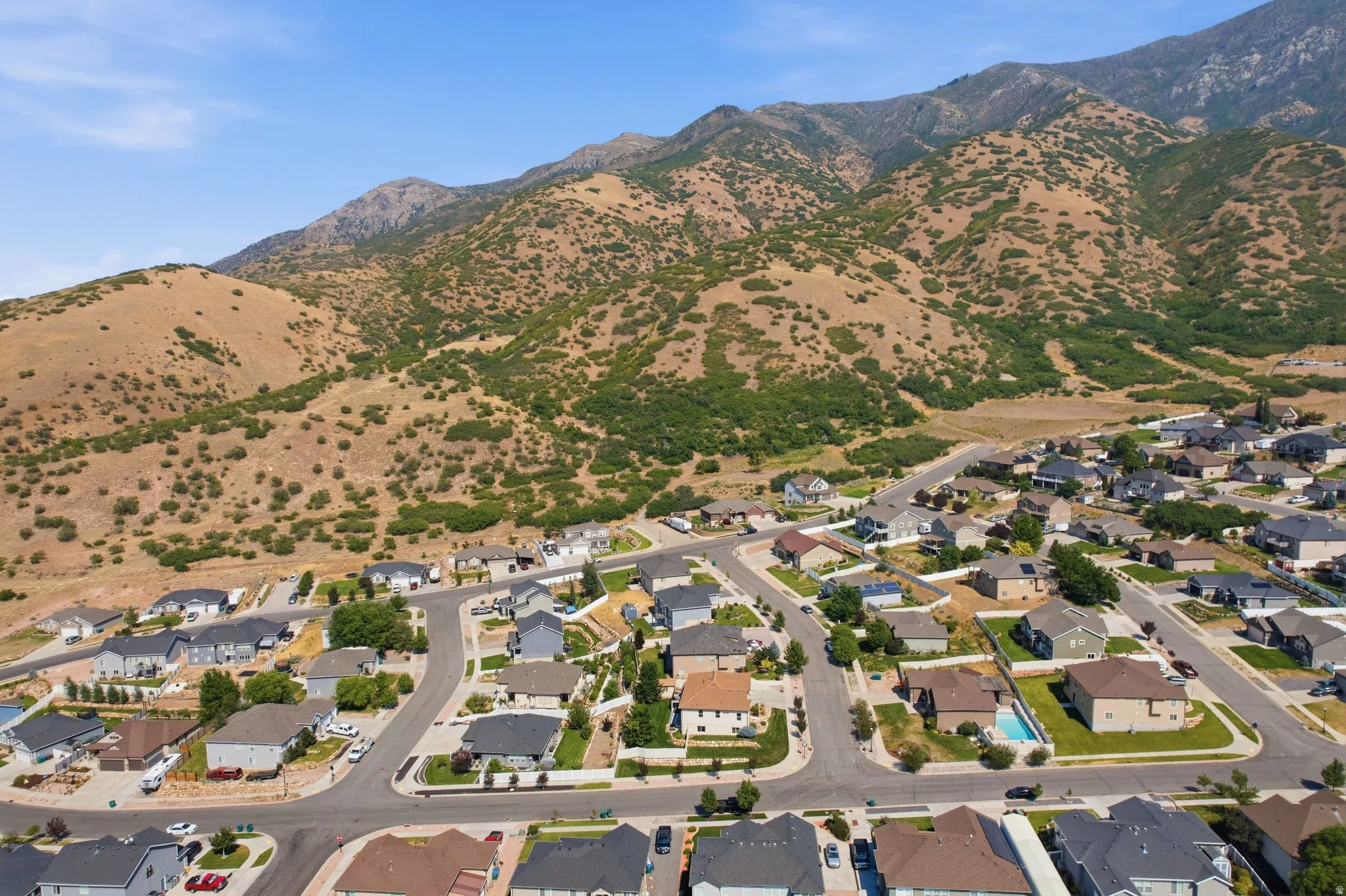 Aerial view of this residential community nestled in a valley with rolling, vegetation-dotted hillsides