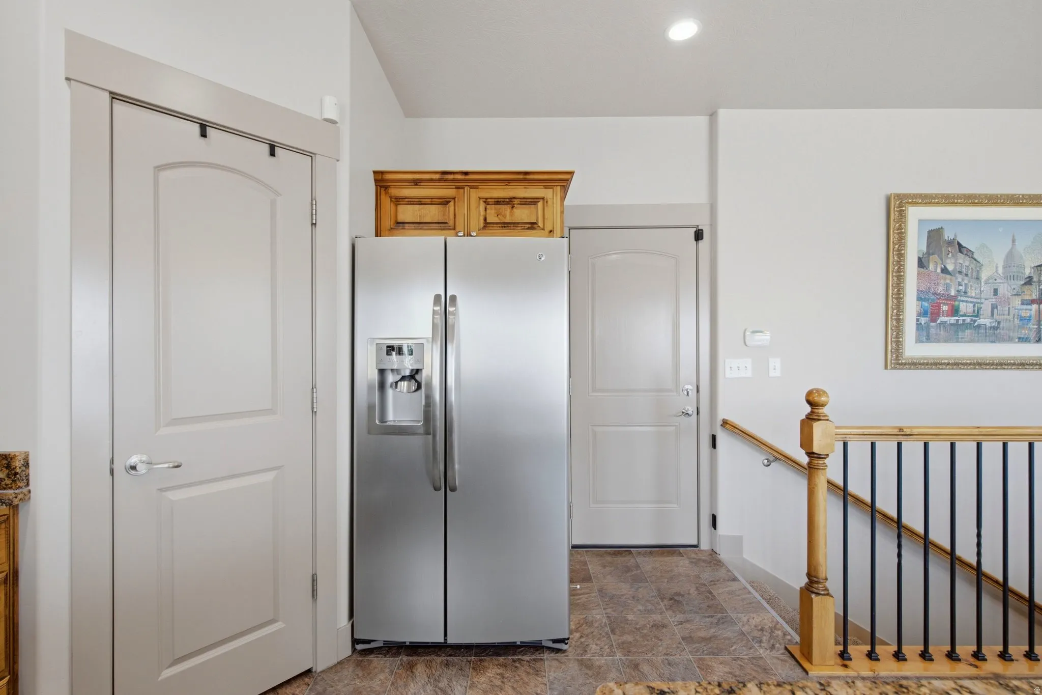 Spacious kitchen featuring stainless steel side-by-side refrigerator with ice and water dispensers, white cabinetry, and tile flooring
