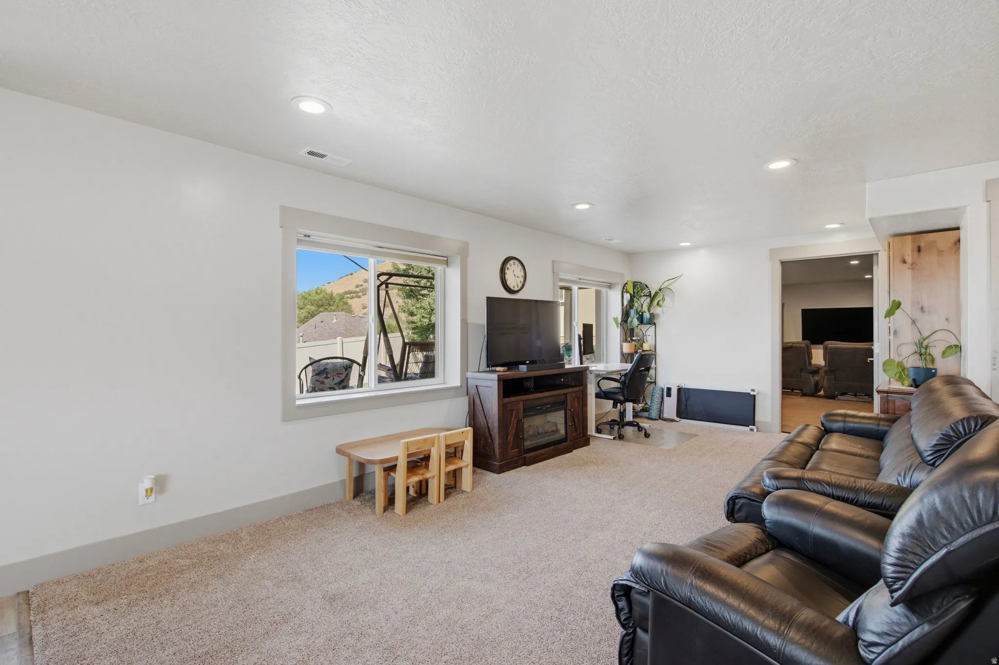 Carpeted living area featuring recessed lighting, a built-in media console with fireplace, and a window with mountain scenery