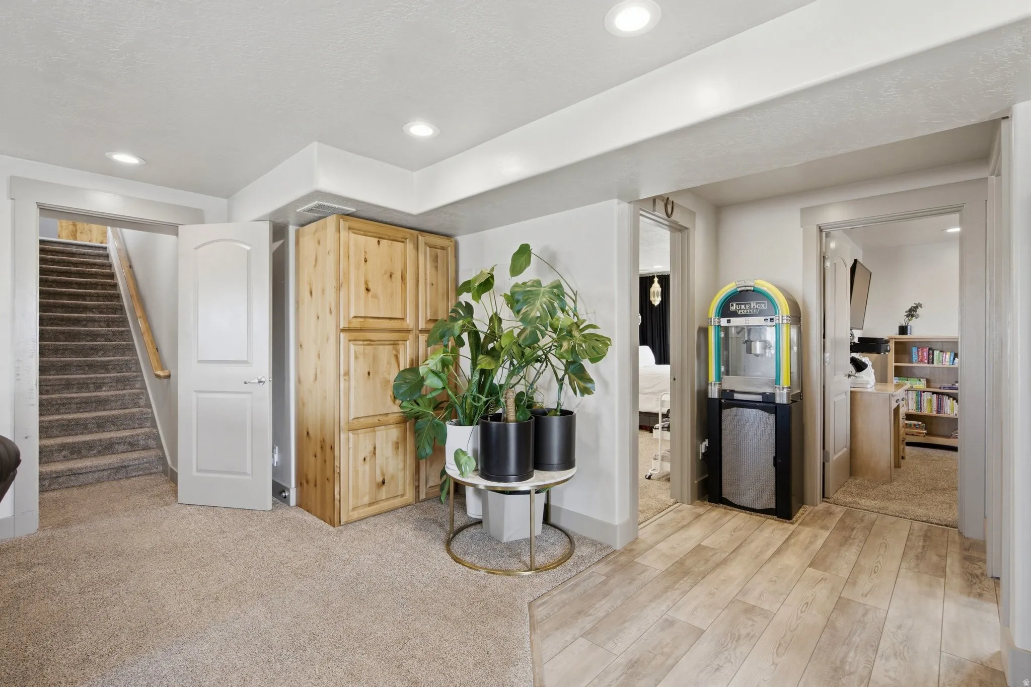 Bright and open basement recreation area featuring wood-finish flooring, recessed ceiling lighting, and multiple doorways providing access to adjoining spaces