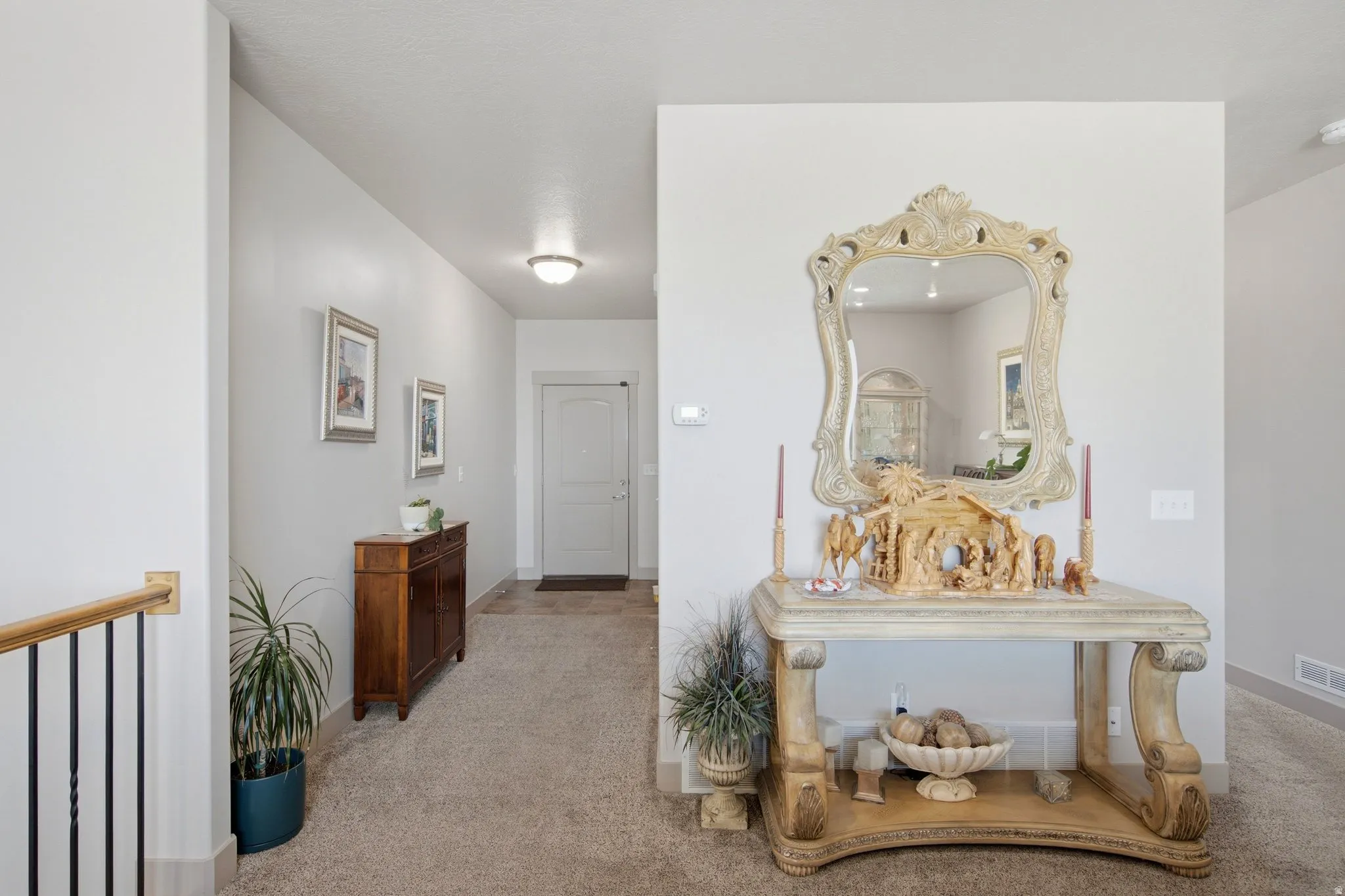 Elegant upper-level hallway featuring neutral carpeting, crisp white walls, and architectural detail through a decorative console table with ornamental mirror