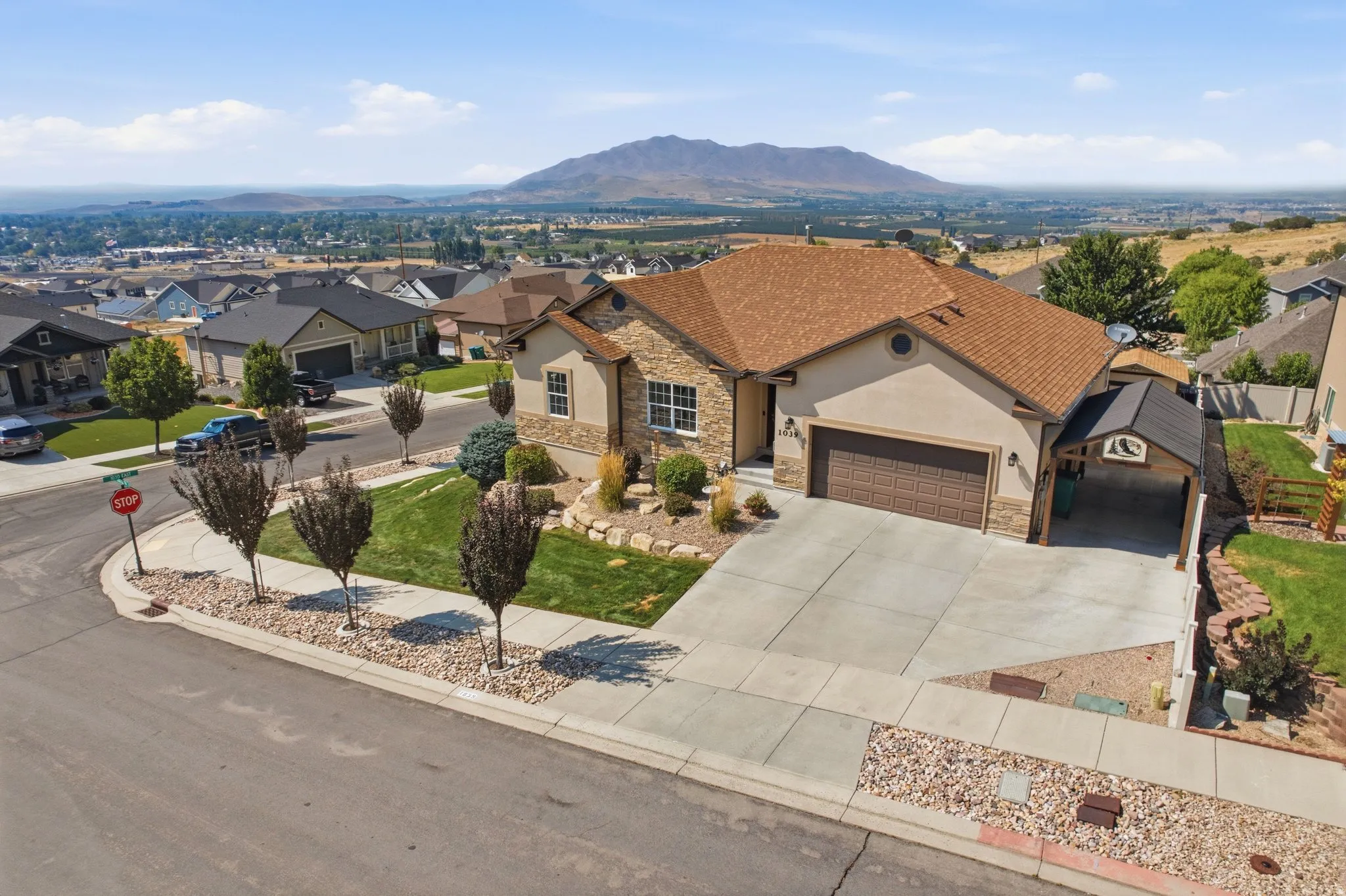Stunning single-story residence showcasing a terracotta tile roof, stucco exterior with stone accents, and a three-car garage with bronze-finish doors