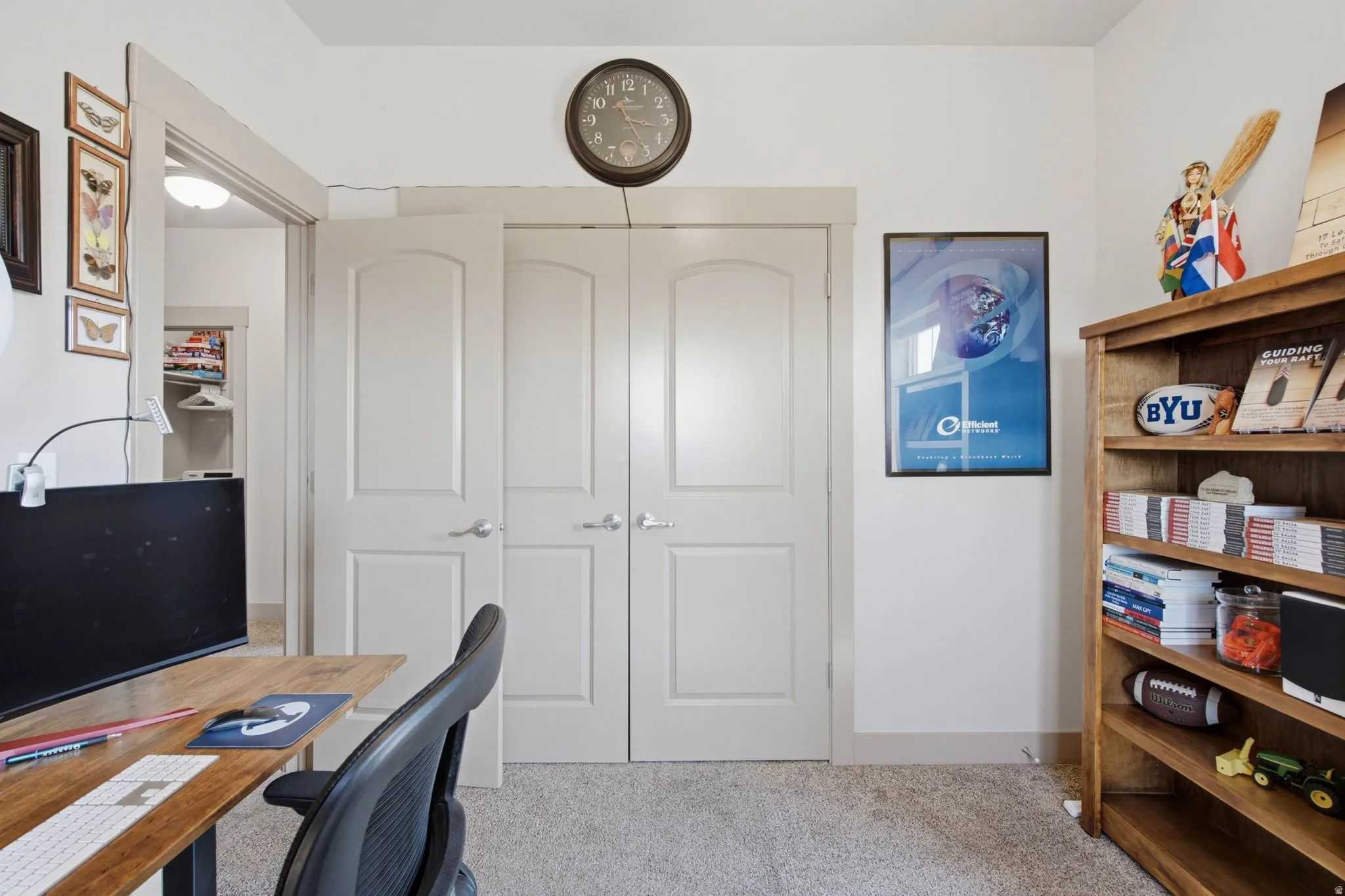 Home office featuring a wood-finish desk, ergonomic task chair, and built-in wood shelving with storage