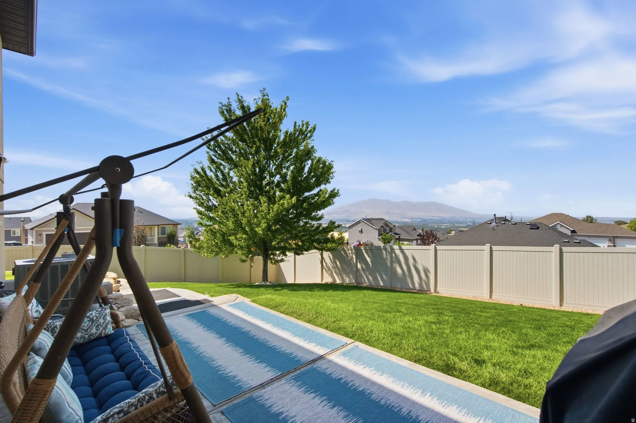 Expansive backyard oasis featuring a meticulously manicured lawn, mature shade trees, and ornamental landscaping