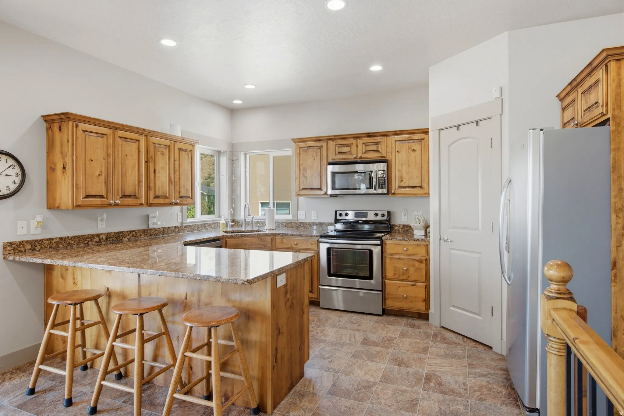 Kitchen featuring wood cabinetry, granite-look countertops, stainless steel appliances, recessed lighting, and tile flooring