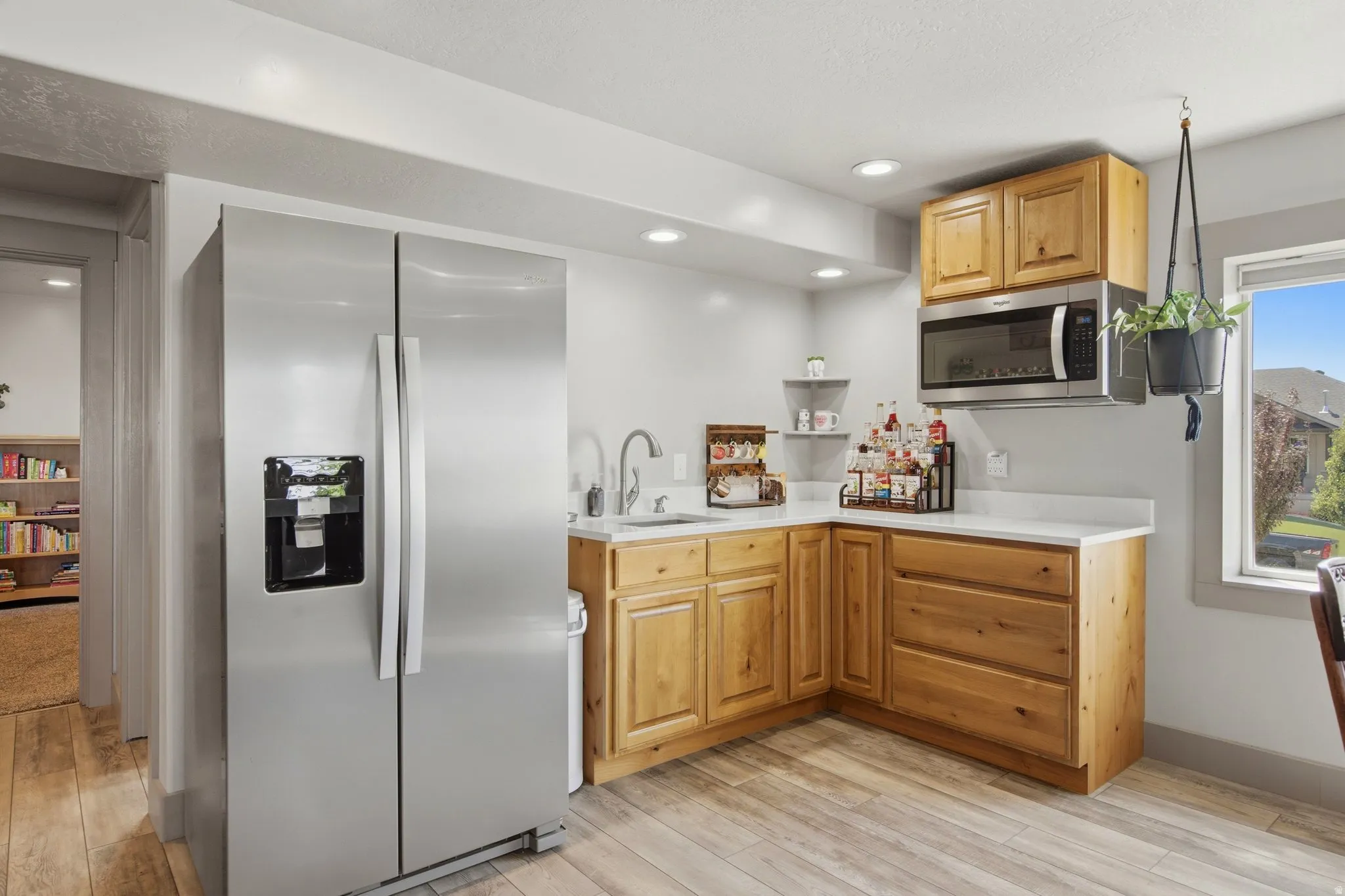 Bright kitchen featuring stainless steel side-by-side refrigerator with ice and water dispensers, wood-finish cabinetry with ample storage, white quartz countertops, and a modern single-handle faucet