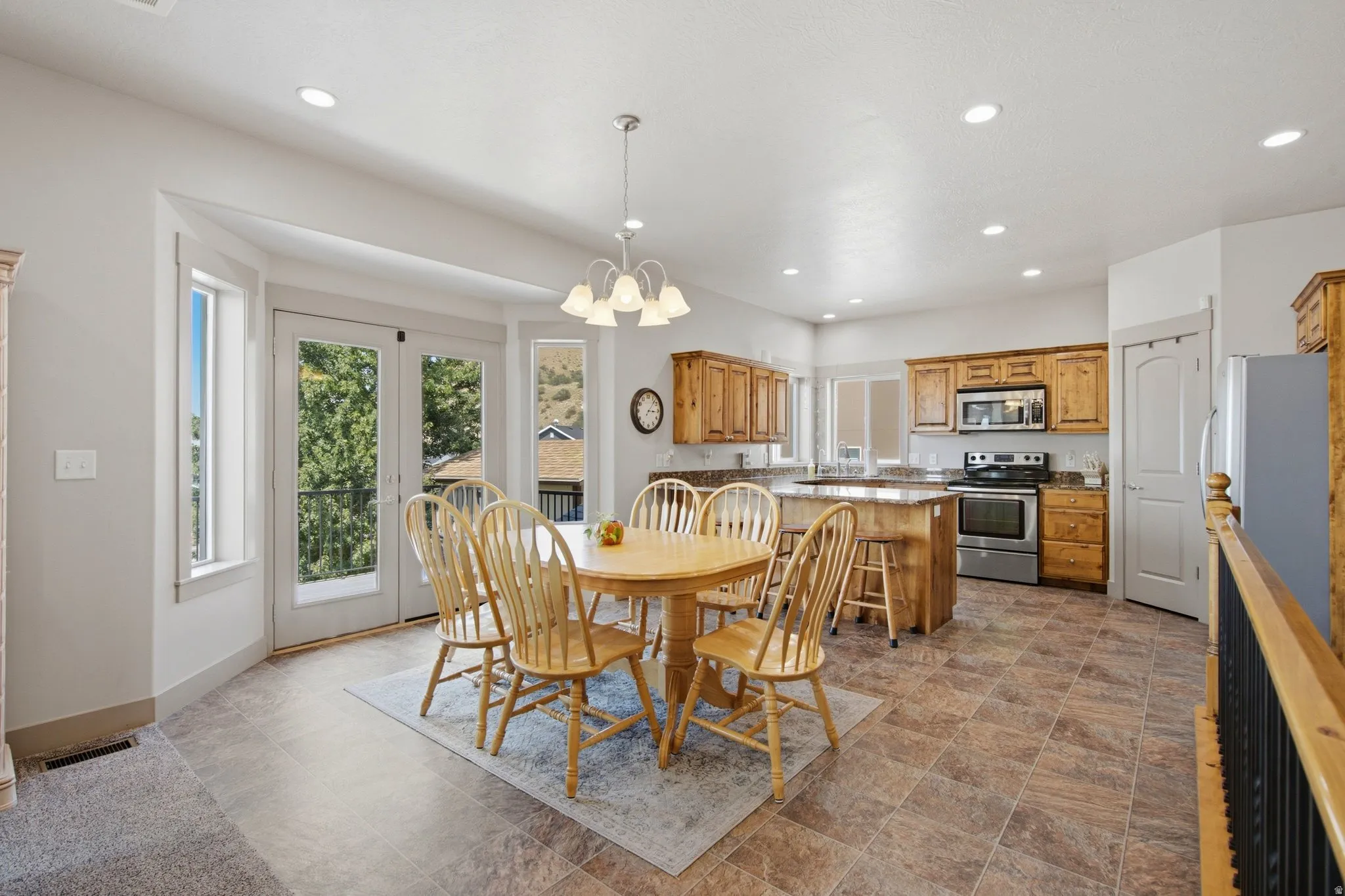 Open-concept kitchen and dining area featuring wood cabinetry, stainless steel appliances, a center island with bar seating, and tile flooring