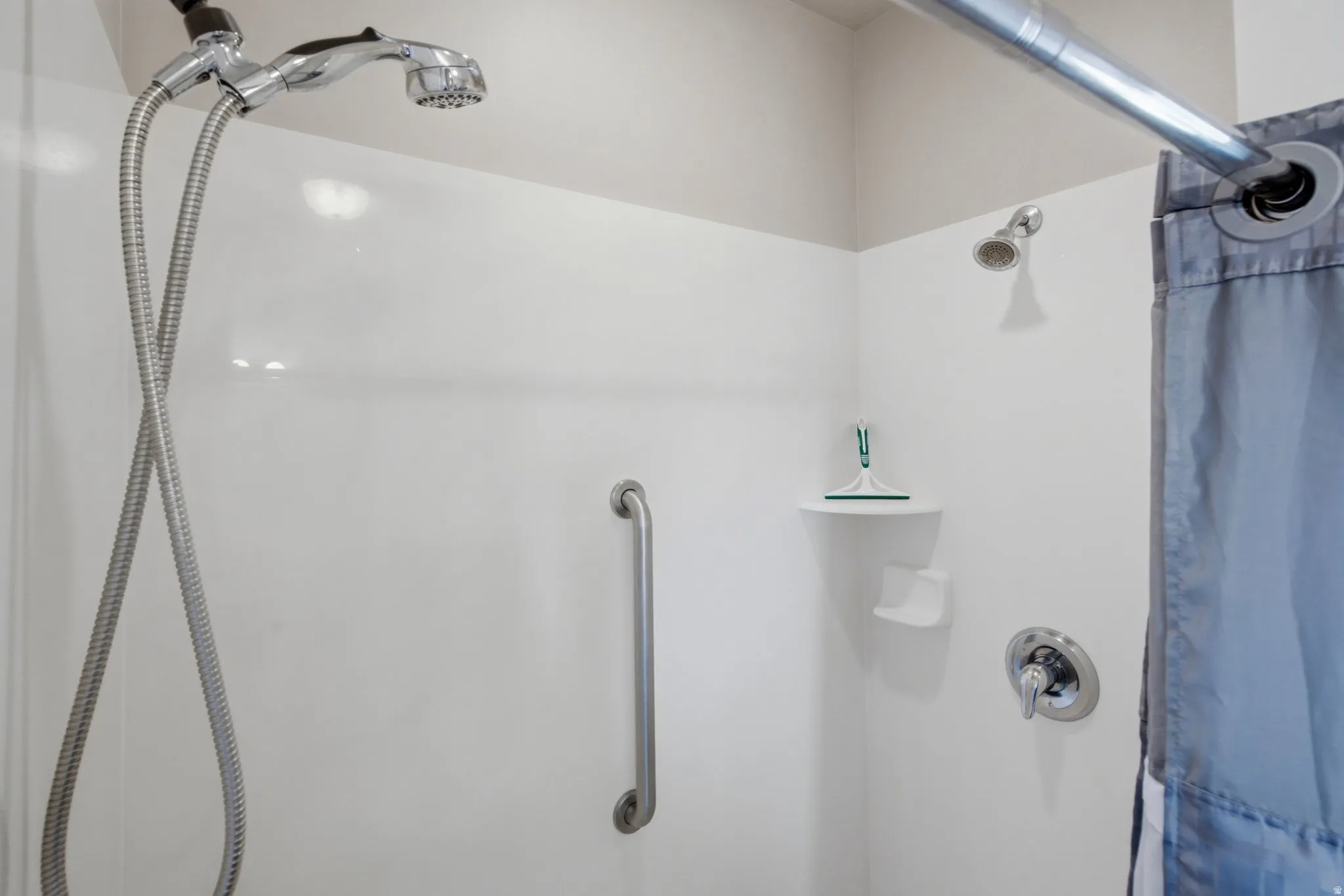 Contemporary shower enclosure featuring clean white subway tile surround, chrome fixtures, and dual showerheads with handheld spray option