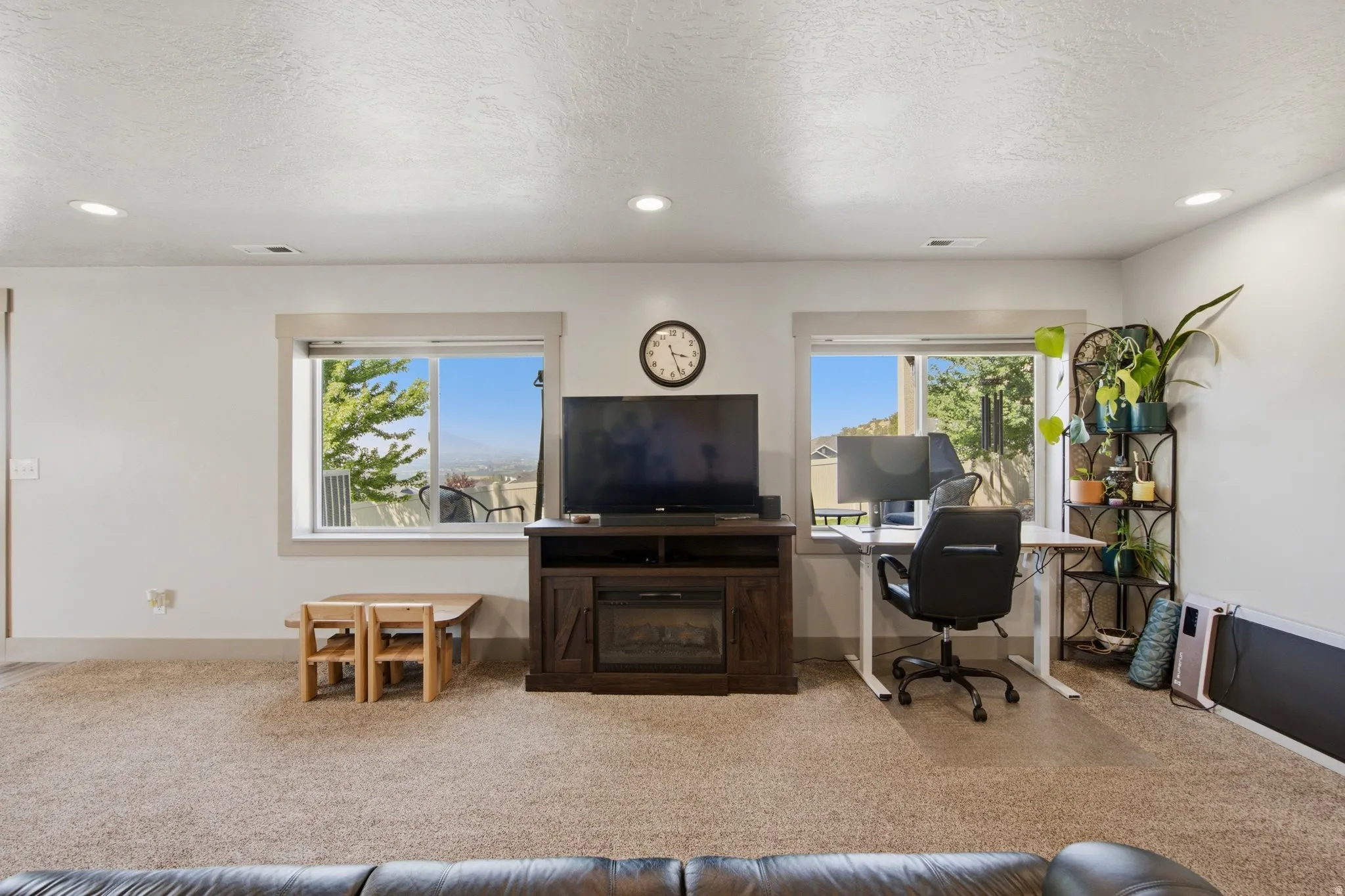 Spacious open-concept living area featuring neutral carpet flooring, recessed ceiling lighting, and dual sliding glass doors with natural light