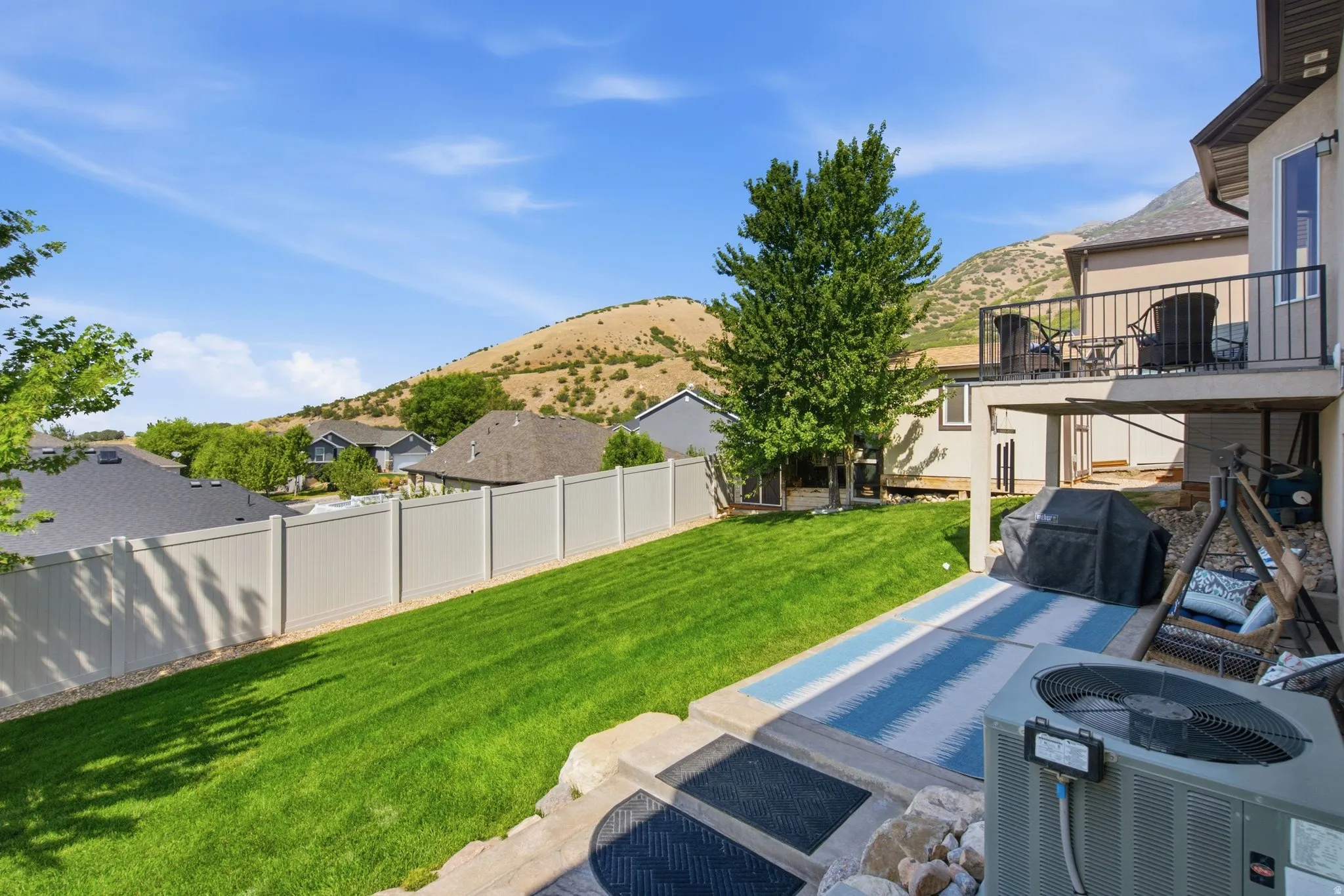 Expansive backyard oasis featuring a manicured lawn, mature landscaping, and heated spa with integrated hot tub
