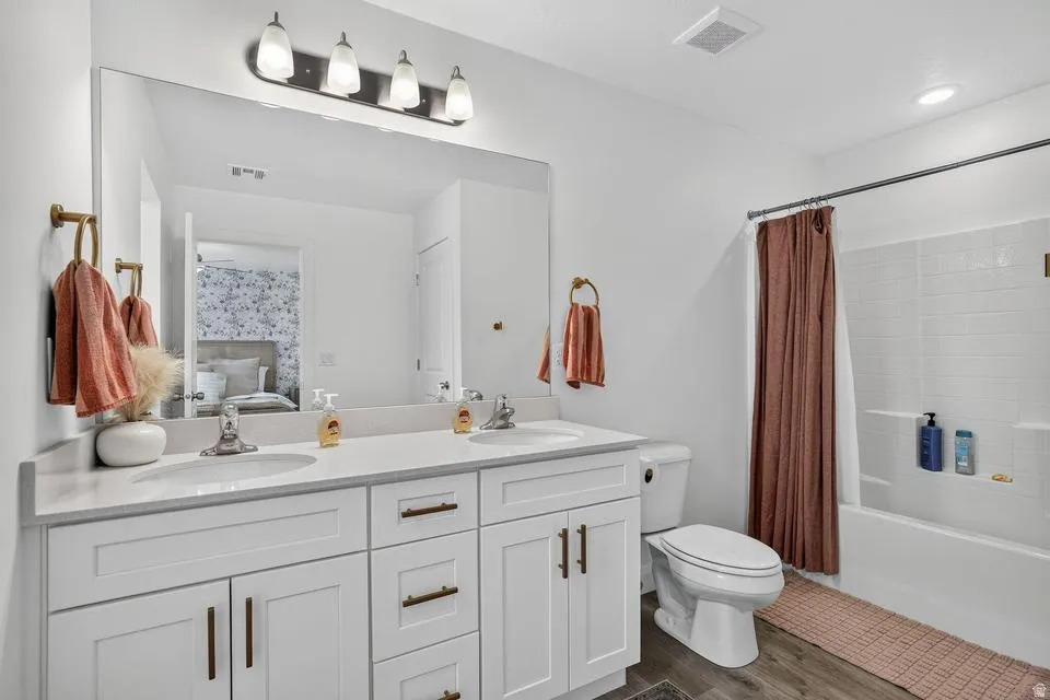 Spa-inspired primary bathroom showcasing a dual-sink vanity with white cabinetry, brushed metal hardware, and a quartz countertop