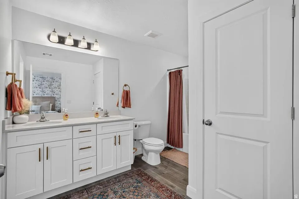 Spa-inspired primary bathroom featuring a double-sink vanity with white cabinetry, brushed brass hardware, and a large framed mirror