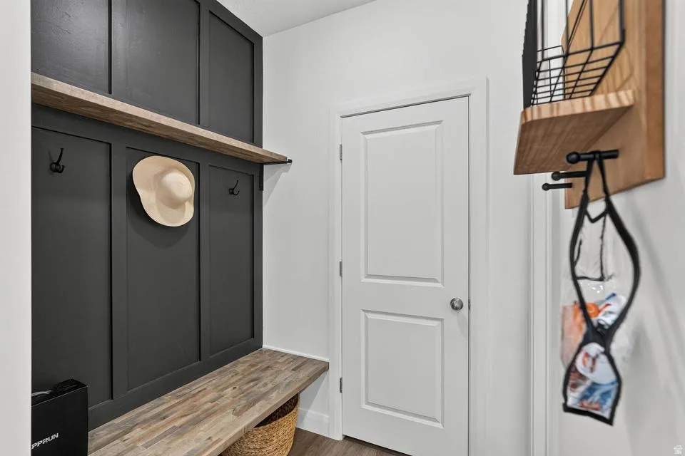 Stylish mudroom entry featuring a dramatic black shiplap accent wall with integrated shelving and hooks, wood-finish floating bench with cork detailing, and abundant storage solutions