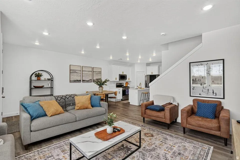 Bright, open-concept living area featuring recessed ceiling lighting, wood-finish flooring throughout, and a neutral color palette