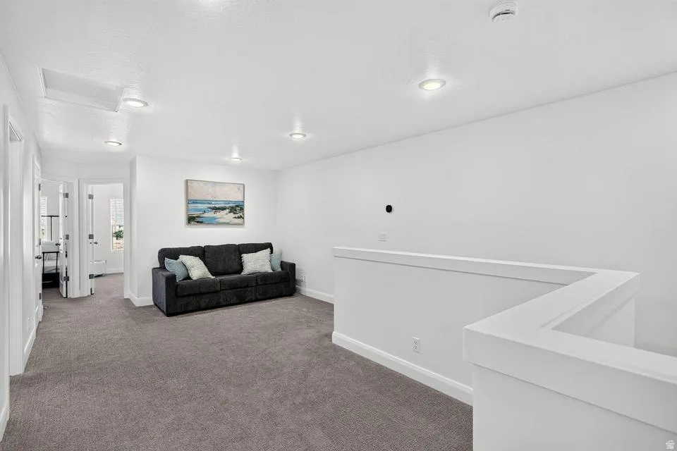 Carpeted loft area featuring recessed lighting, a white painted half-wall railing, and white walls
