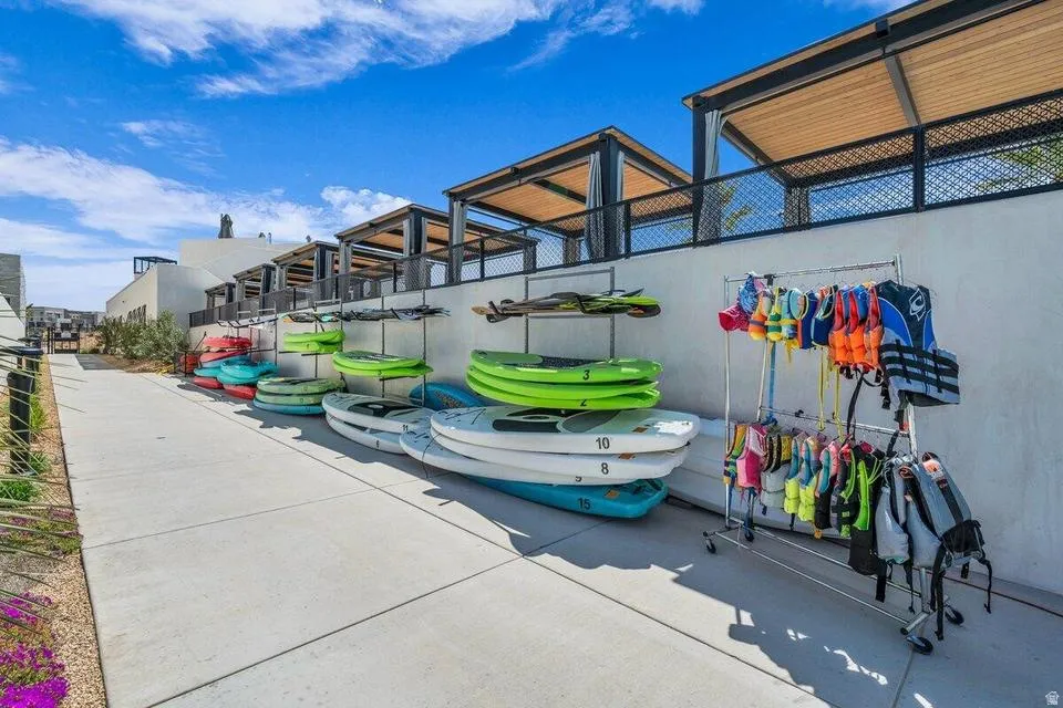 Dedicated recreation area featuring multiple kayaks and water sports equipment storage, complemented by a covered pavilion structure with metal framing and shade panels
