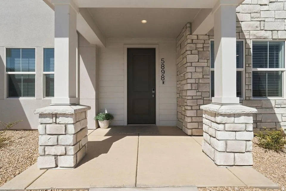 Welcoming front entry showcasing a dark wood door with sidelights, flanked by white-painted brick pillars and complementary white trim