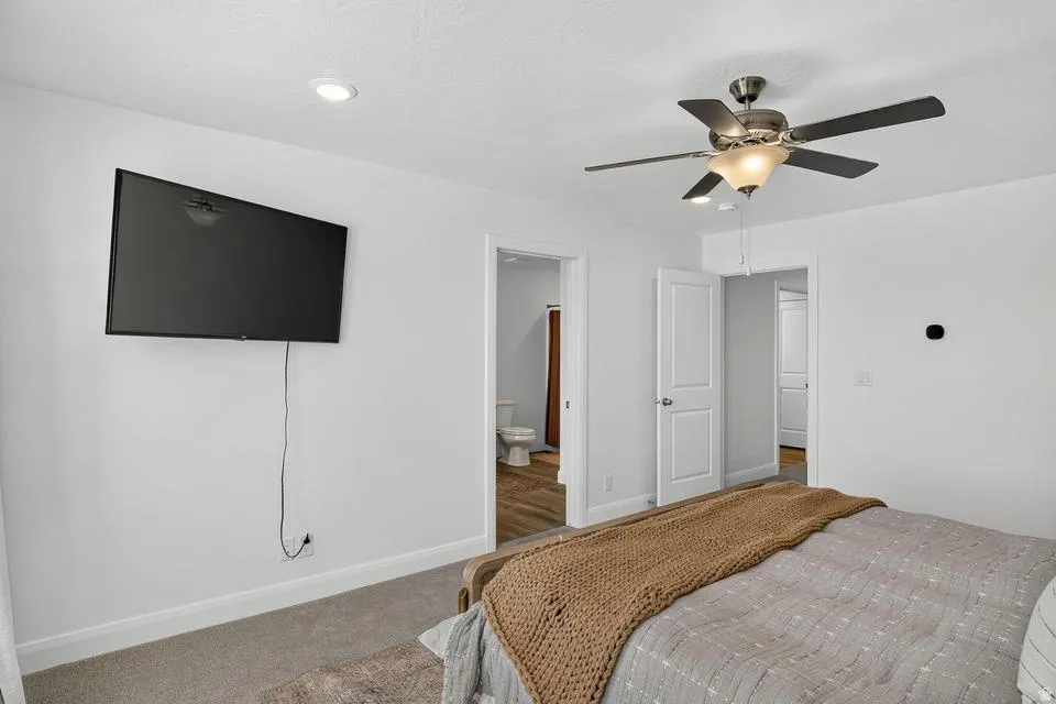 Spacious primary bedroom featuring neutral carpet flooring, recessed ceiling lighting, and a ceiling fan with integrated light fixture