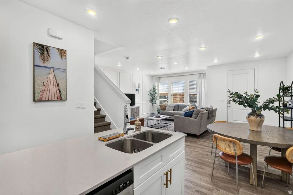 Open-concept living featuring a modern kitchen with white cabinetry, stainless steel dual-basin sink, and light wood-finish countertops that extend into the dining area
