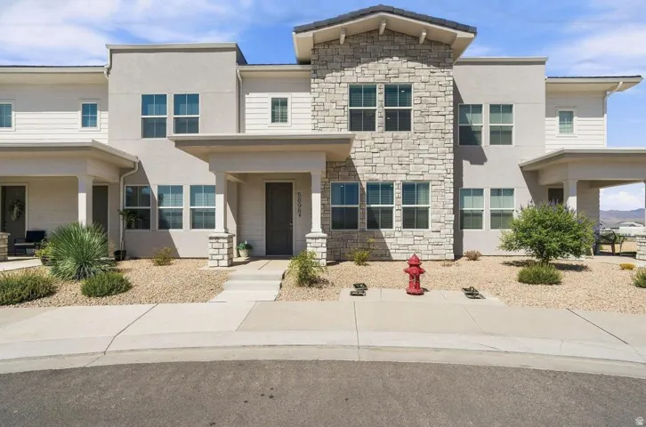Contemporary townhome featuring a striking mixed-material facade with cream-colored stucco and natural stone accents