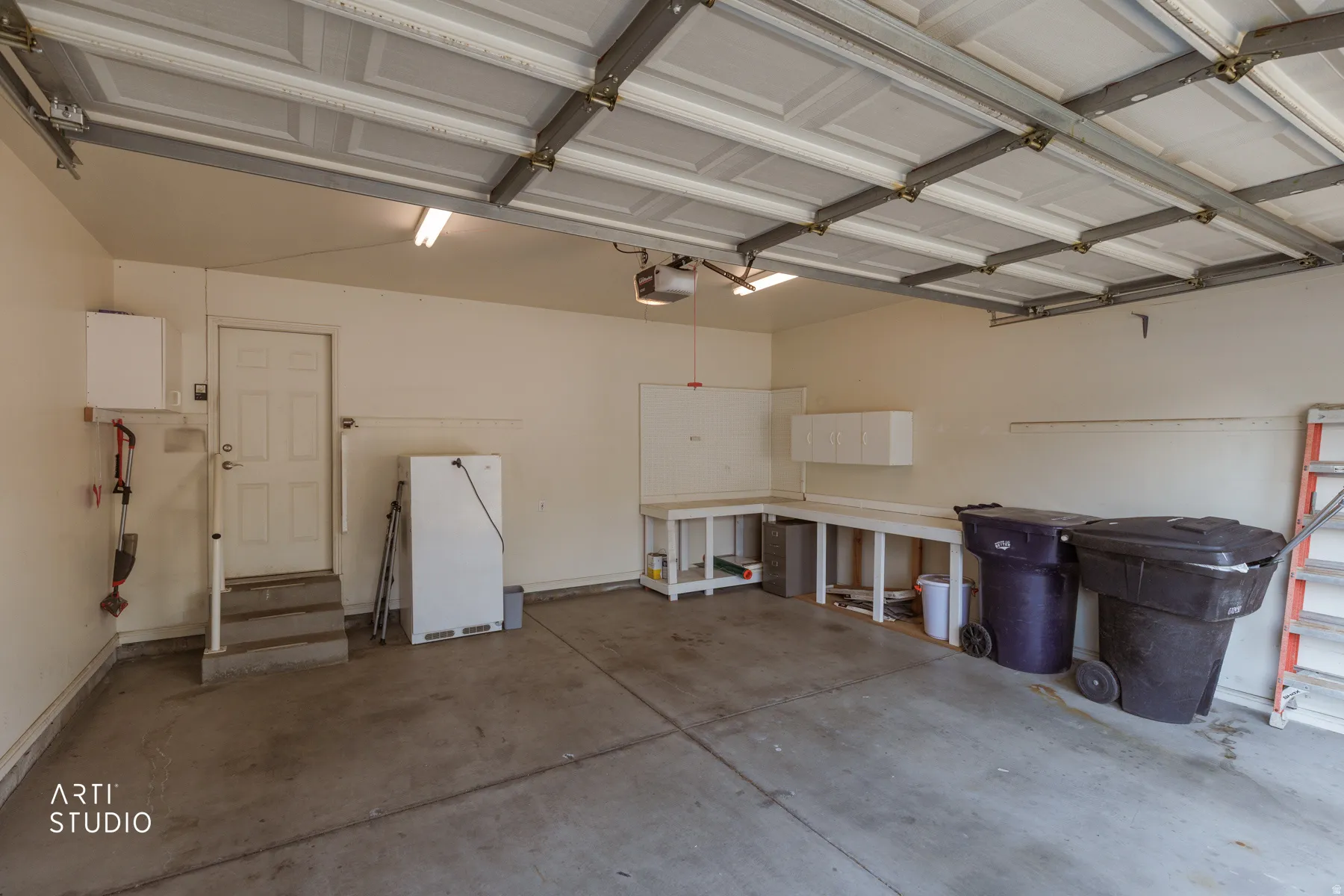 Spacious garage with polished concrete flooring, overhead LED lighting, and metal-framed ceiling structure