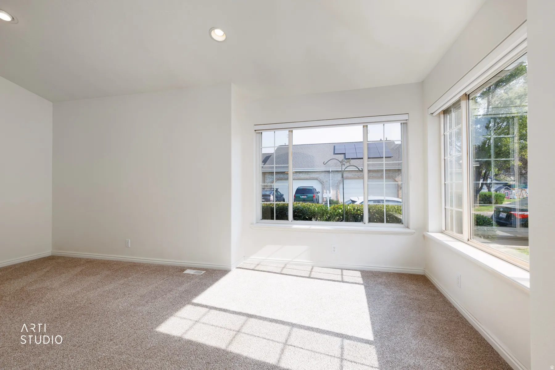 Bright corner room flooded with natural light through expansive multi-pane windows and glass sliding doors