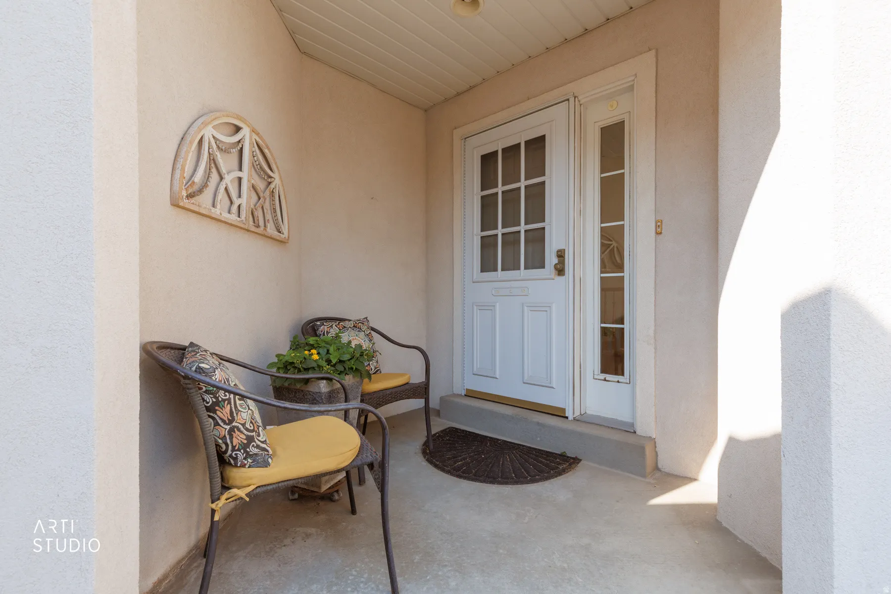 Recessed entry featuring a paneled front door with grid-patterned glass, a sidelight, and stucco exterior walls