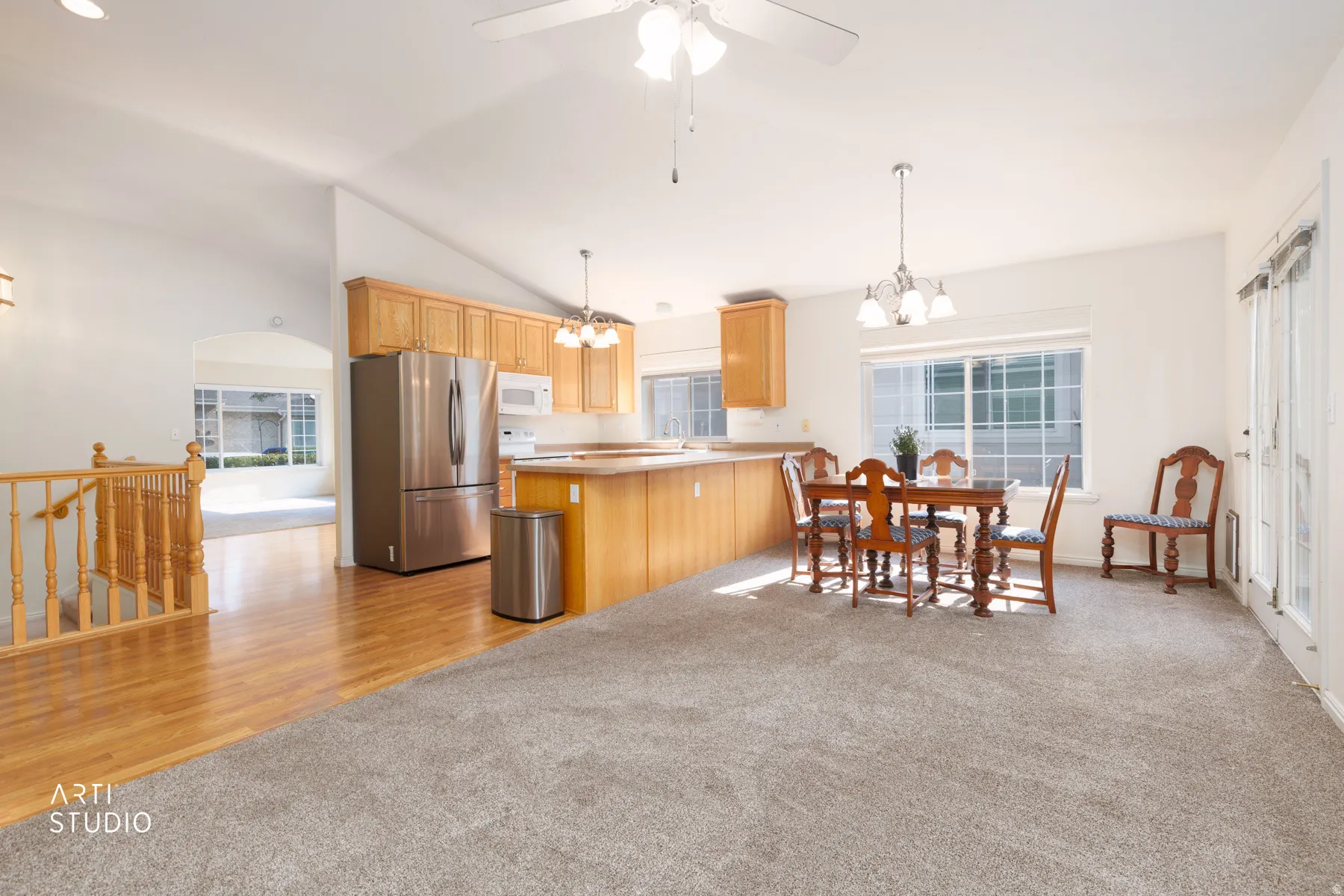 Open-concept kitchen and dining area featuring wood-finish cabinetry, stainless steel appliances including a French-door refrigerator, and a centered island with seating