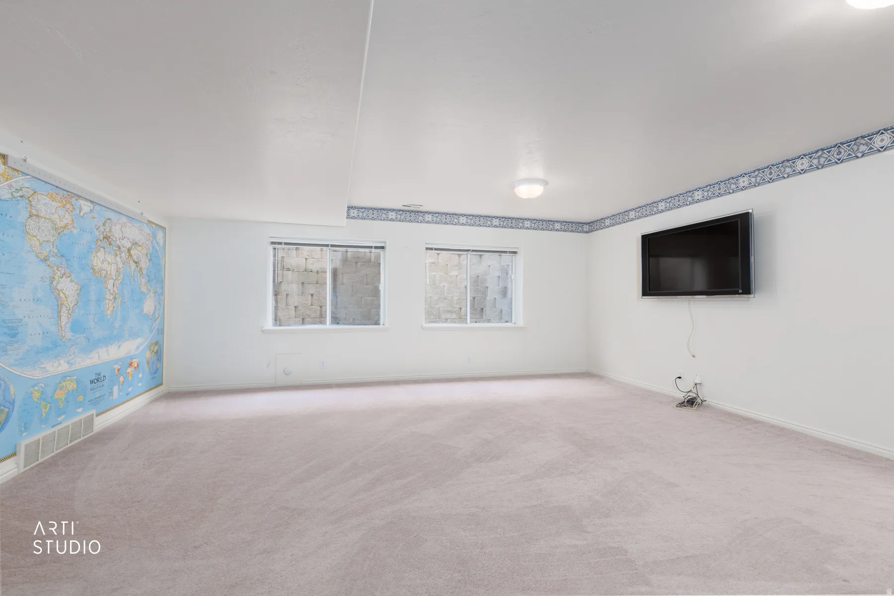 Spacious room featuring neutral carpeting, recessed ceiling lighting, and decorative border trim