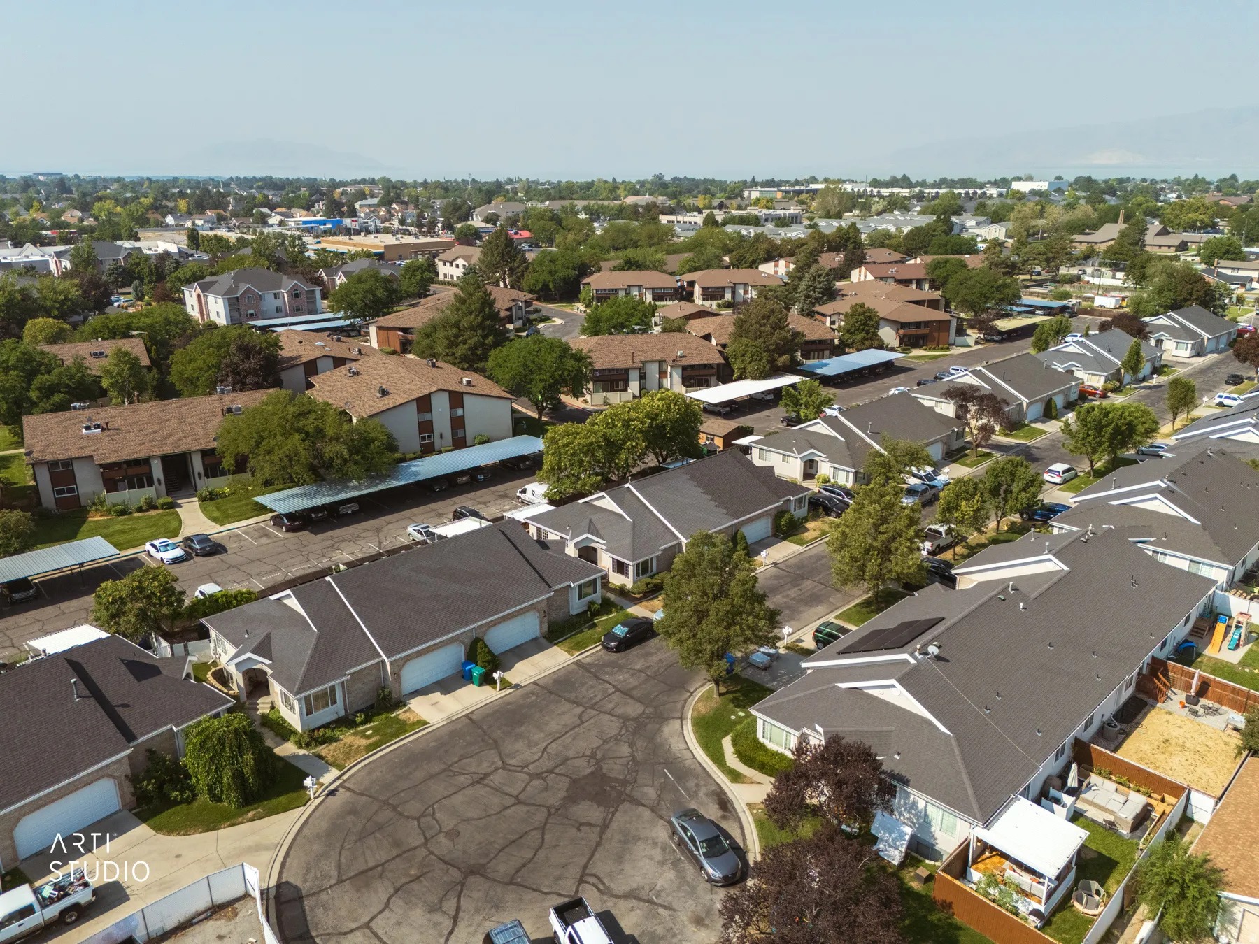 Aerial view of this established residential community featuring single-family homes with dark composition roofing, manicured landscaping, and mature tree coverage throughout the neighborhood