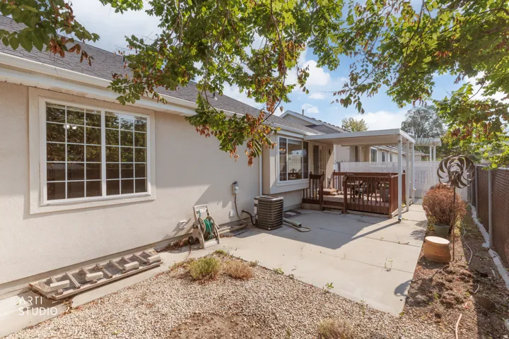 Backyard retreat featuring mature shade trees, expansive concrete patio with multiple entertaining zones, and low-maintenance gravel landscaping