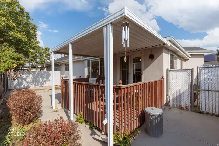 Modern covered patio featuring white structural columns, wood-finish railing, and polished concrete flooring